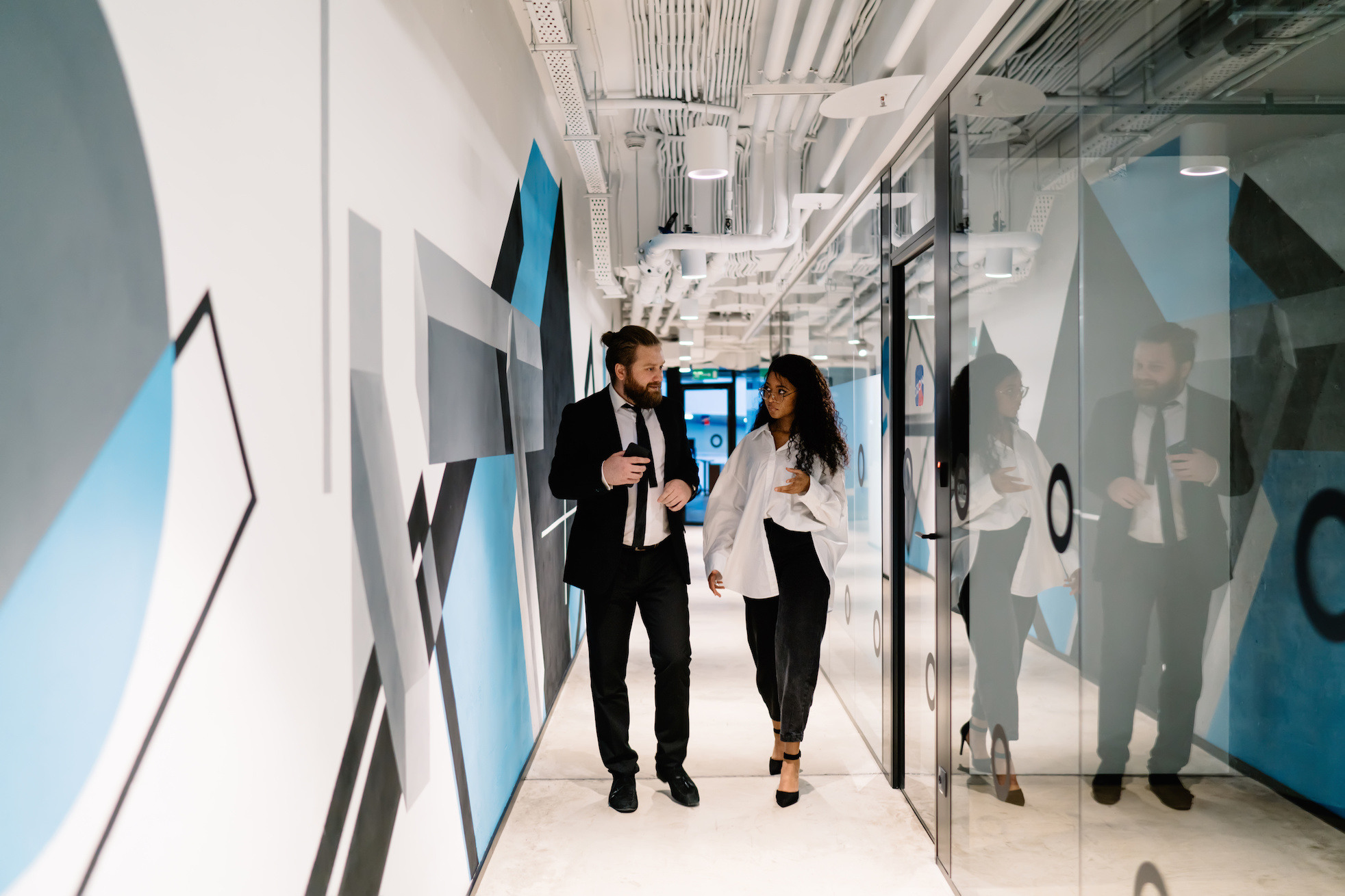 business-people-discussing-in-office-corridor-whil-2023-11-27-05-26-23-utc